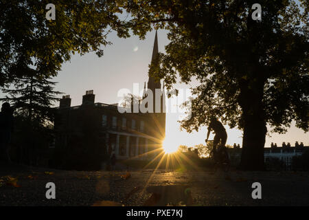 Londra, Regno Unito. 22 ottobre, 2018. Regno Unito meteo, bellissima alba autunnale in Clissold Park, Stoke Newington, Londra. Vista verso Clissold casa con la chiesa di Santa Maria sul lato destro. Silhouette di un ciclista. Credito: Carol moiré / Alamy Live News Foto Stock