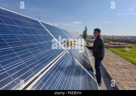 (181022) -- URUMQI, Ottobre 22, 2018 (Xinhua) -- abitante Pan Linqi pulisce i pannelli solari in Hami, a nord-ovest della Cina di Xinjiang Uygur Regione autonoma, Sett. 21, 2018. Xinjiang ha visto un aumento della produzione di elettricità da energia pulita. Secondo una griglia di Stato nello Xinjiang potenza elettrica Co., Ltd., energia eolica e solare generato 27.81 miliardi e 9,07 miliardi di chilowattora (kwh) di elettricità, rispettivamente, nei primi nove mesi del 2018 nella regione. Con abbondanza di energia eolica e solare risorse, Xinjiang è un pioniere nell'uso di nuova energia in Cina, con installato il nuovo-energia avente capacità exc Foto Stock