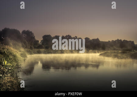 Campagna alba fiume nebbia paesaggio paesaggio con nebbia tranquillo specchio d'acqua e drammatico buio moody sky Foto Stock