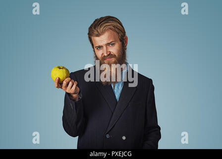 Sono stanco di questi regimi alimentari sani. Closeup ritratto infelice giovane uomo nutrizionista personal fitness trainer holding e offrendo un apple con skeptica Foto Stock