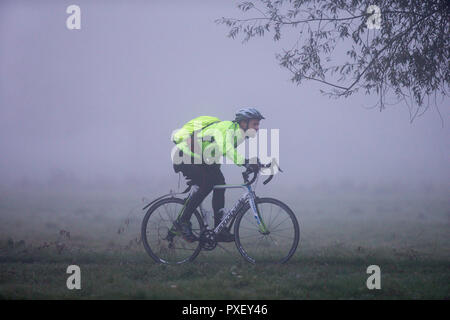 Persona in sella a una moto dal fiume Cam in Cambridge in la mattina presto su un foggy nebbioso giorno Foto Stock