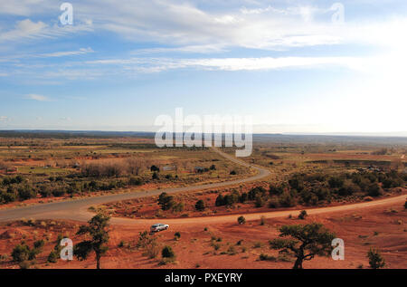 La valle piatta di Lukachukai, terra Navajo in Arizona, Stati Uniti d'America, mostrando l'orizzonte, il deserto, la strada, gli alberi e il cielo luminoso e una piccola automobile Foto Stock