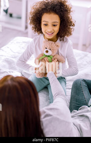 Tipo persona di sesso femminile prendendo orso giocattolo da ragazza Foto Stock