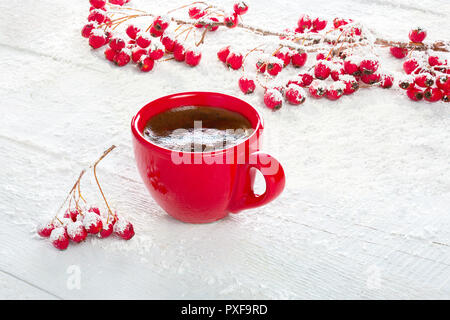 Red tazza di caffè e dei rami con bacche di biancospino su un vecchio bianco sullo sfondo di legno. Foto Stock