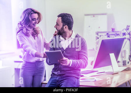 Elegante donna che indossa pantaloni e camicia beige in piedi a sentire il marito Foto Stock