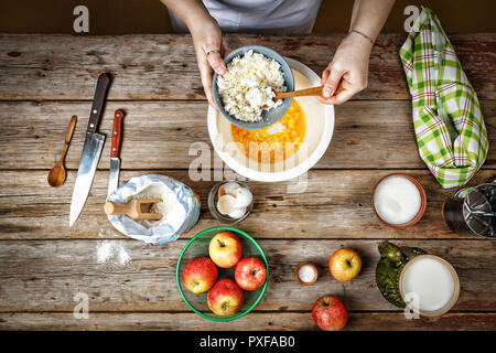 Femmina chef prepara il ripieno per cuocere la torta al forno, gli ingredienti in cucina un tavolo di legno. Il concetto: cucina, ricetta. Vista dall'alto. Foto Stock