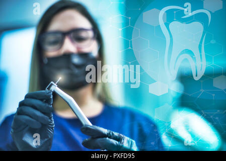 Dentista femmina nella mascherina chirurgica azienda trapano dentistico doppia esposizione strutture molecolari e denti Foto Stock