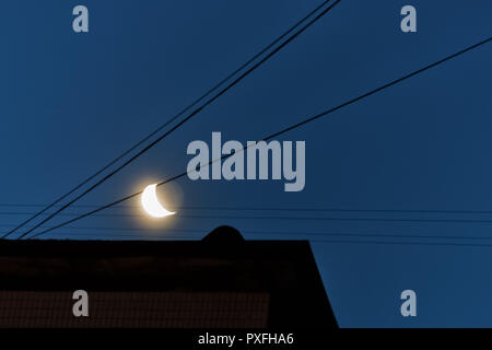 Paesaggio, giovani, crescendo, luna calante in blu scuro cielo notturno con fili sopra i tetti della città. Foto Stock