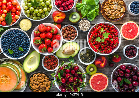 Cibo sano e selezione. Super alimenti per la colazione, bocce con organici frutta fresca e bacche assortiti, semi e i dadi sul tavolo. Dieta vegetariana concept Foto Stock