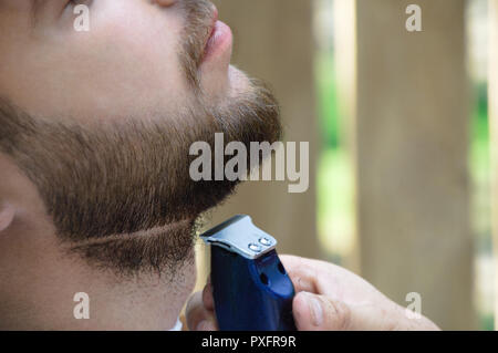 La mano del rivestimento del barbiere l'uomo con un regolabarba. Close-up. Foto Stock