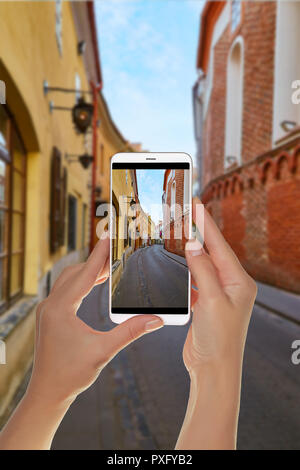 Un turista è di scattare una foto di vuoto street nel centro storico della capitale della Lituania - Vilnius su un telefono cellulare Foto Stock