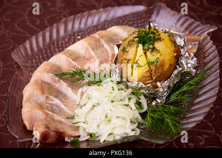 Patate al forno con pesce marinato e cipolle sulle piastre a forma di pesce. Foto Stock
