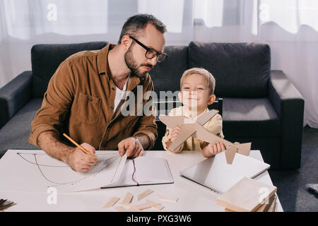 Padre in occhiali e carino piccolo figlio di modellazione piano assieme a casa Foto Stock