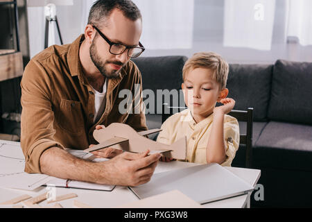 Padre in occhiali e carino piccolo figlio di modellazione piano assieme a casa Foto Stock