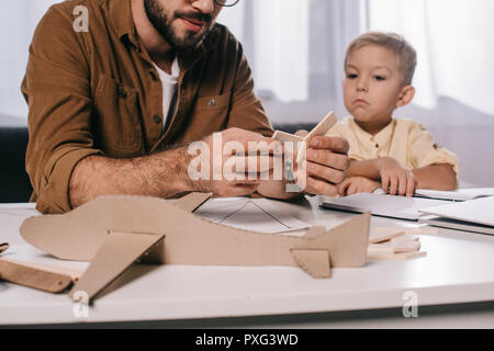 Ritagliato colpo di padre e figlio piccolo giocattolo di modellazione piano assieme a casa Foto Stock