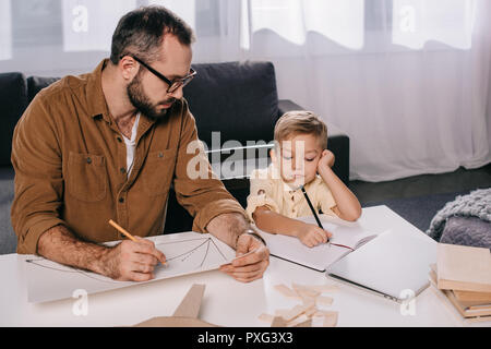 Padre e figlio piccolo disegno mentre la modellazione di insieme a casa Foto Stock