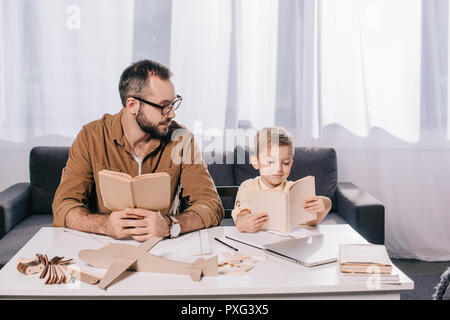 Padre e figlio azienda libri mentre la modellazione di piano a casa Foto Stock