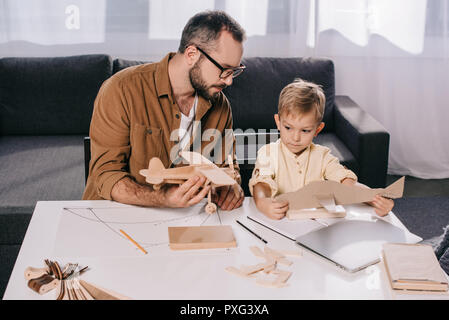 Padre in occhiali e carino piccolo figlio di piani di modellazione insieme a casa Foto Stock