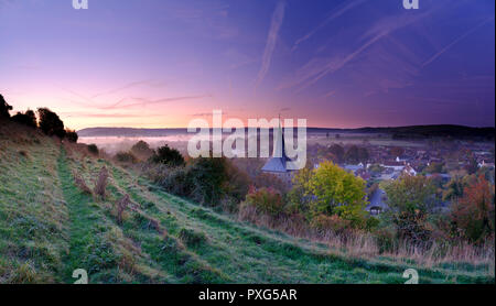 Di prima mattina nebbia autunnale su East Meon villaggio con Butser Hill e il South Downs in background, South Downs National Park, Hampshire, Regno Unito Foto Stock