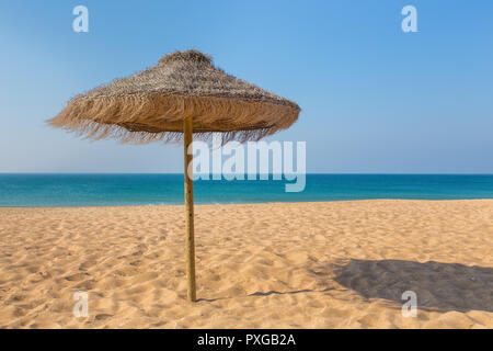 Uno di paglia ombrellone in spiaggia al mare blu Foto Stock