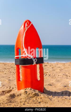 Boa arancione permanente sulla spiaggia sabbiosa a mare blu Foto Stock