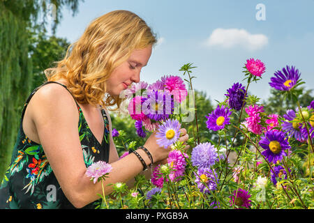 Giovane olandese redhead donna odore di fiori d'estate in giardino Foto Stock