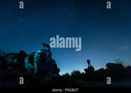 Nota del redattore: Foto scattata con una lenta velocità di otturazione un piano passa da come un uomo stargazes a Brimham Rocks in Yorkshire come Orionid Meteor doccia raggiunge il suo picco. Foto Stock