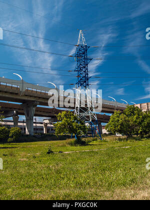 Un traliccio metallico sorge su un green glade vicino alla superstrada costruzione in estate in una giornata di sole a San Pietroburgo Foto Stock