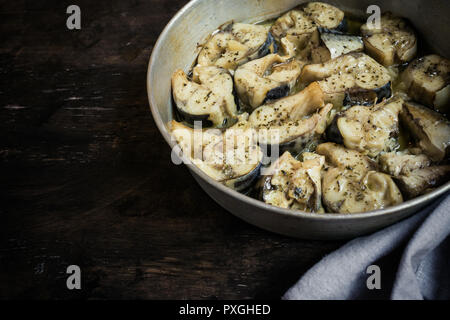 Pesce al forno sgombro in una padella, su un sfondo di legno. Fette di cotto atlantico Sgombro/ Foto Stock