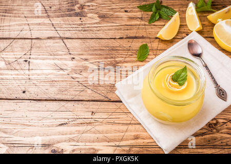 In casa limone cagliata in vasi di vetro con limoni freschi, rustico in legno copia di sfondo spazio. Foto Stock