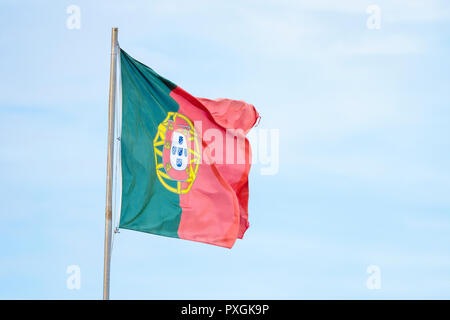 Bandiera portoghese sventola sul forte vento con cielo blu dietro Foto Stock