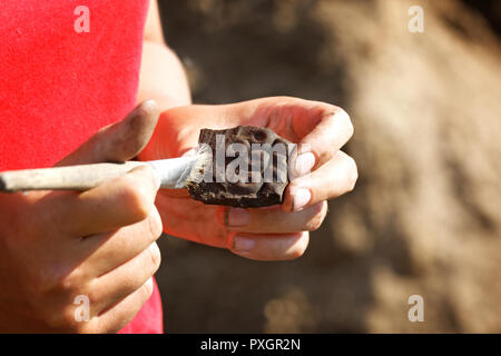 Archeologo maniglie con cautela il trovare - parte medievale di recipiente di argilla.un modello primitivo è premere sulla sua superficie Foto Stock