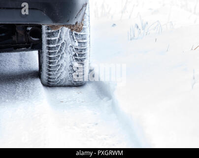 Pneumatico invernale sulla neve country road. Bassa angolazione da auto retro Foto Stock