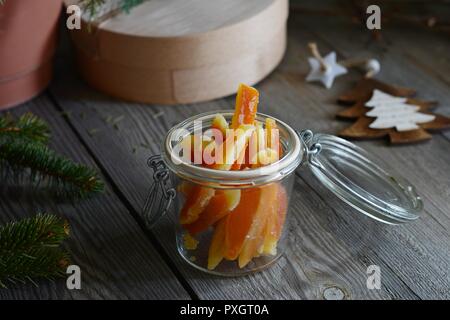 Arancia candita fette in un barattolo di vetro per il Natale. Bellissime decorazioni di Natale, in background. Foto Stock