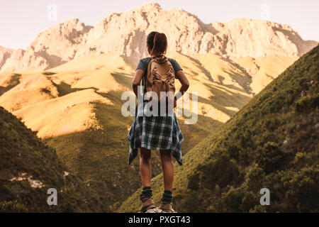 La donna si erge su una roccia e guarda alle montagne. vista posteriore di un escursionista femmina guardando la vista sulla montagna. Foto Stock