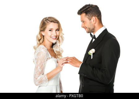 Felice giovane sposa mettendo in anello di nozze sposi sul dito isolato su bianco Foto Stock