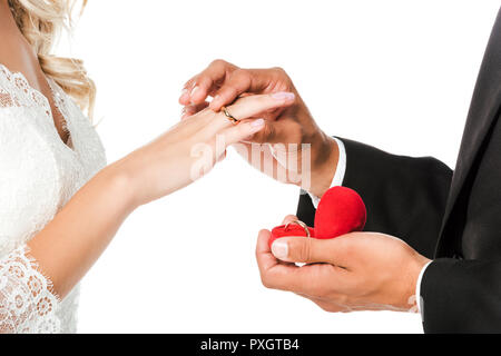 Ritagliato shot di groom mettendo sul matrimonio anello sul dito spose isolato su bianco Foto Stock