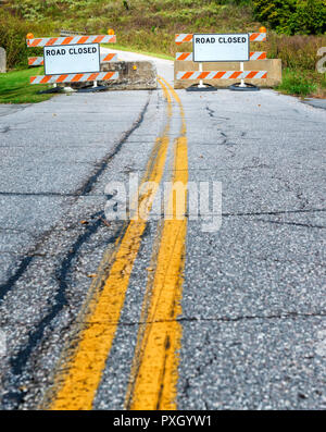 Colpo verticale di due strada chiusa segni su una autostrada incrinato con due linee di colore giallo nel centro. Foto Stock