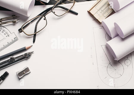 Sul tavolo di legno vi sono disegni, bussole, matita, elastico, righello e temperino e bicchieri. Foto Stock