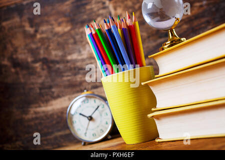 Libri di testo, orologi, Globe e matite su uno sfondo di legno Foto Stock