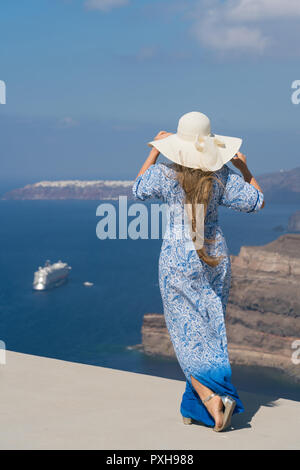 Giovane donna in un bianco e azzurro vestito gode di una passeggiata intorno a Santorini Foto Stock