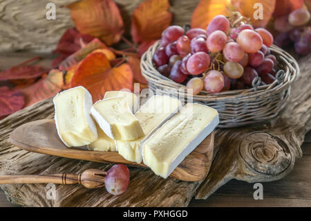 In casa organico bianco Formaggio Brie con uve rosa su una tavola di legno. Foto Stock