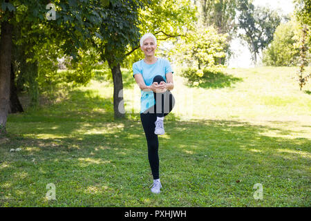 Ritratto di donna senior facendo esercizi streching nel parco Foto Stock