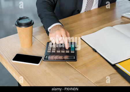 Immagine ritagliata di imprenditore utilizzando la calcolatrice durante il lavoro in ufficio Foto Stock