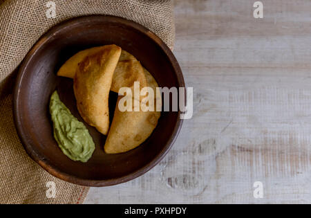 Venezuela e Colombia cibo. Venezuelano di mais tipici empanadas con carne nella terrina di argilla con salsa di avocado. Foto Stock