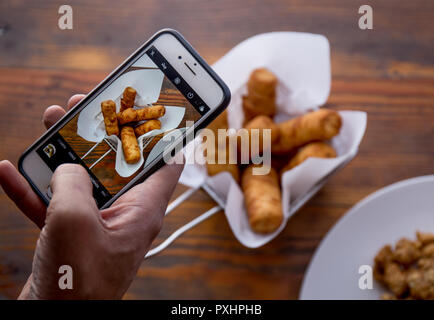 Gli uomini le mani prendendo il cibo foto di TEQUENOS venezuelano dal telefono cellulare. Foto Stock