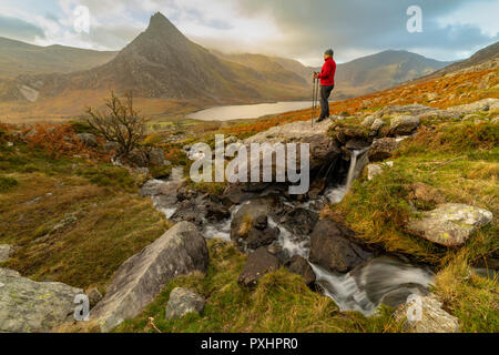 Una montagna di walker tenendo nel bellissimo paesaggio della valle Ogwen e la vetta del monte Tryfan nel Galles del Nord, Regno Unito Foto Stock