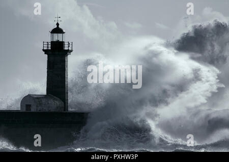 Grandi onde tempestose oltre il vecchio faro. Nei toni del blu. Foto Stock