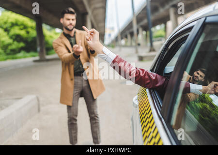 Ragazza in taxi e uomo sulla strada dando le dita tra di loro Foto Stock