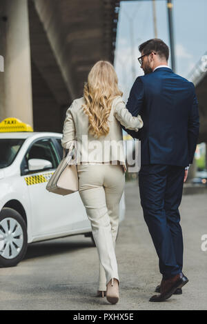 Vista posteriore di un elegante coppia giovane andare insieme al servizio taxi Foto Stock